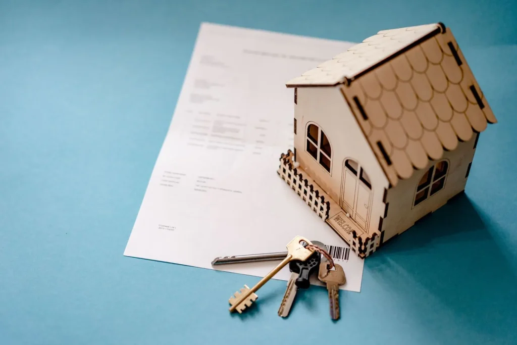 Maqueta de casa de madera con llaves sobre un contrato